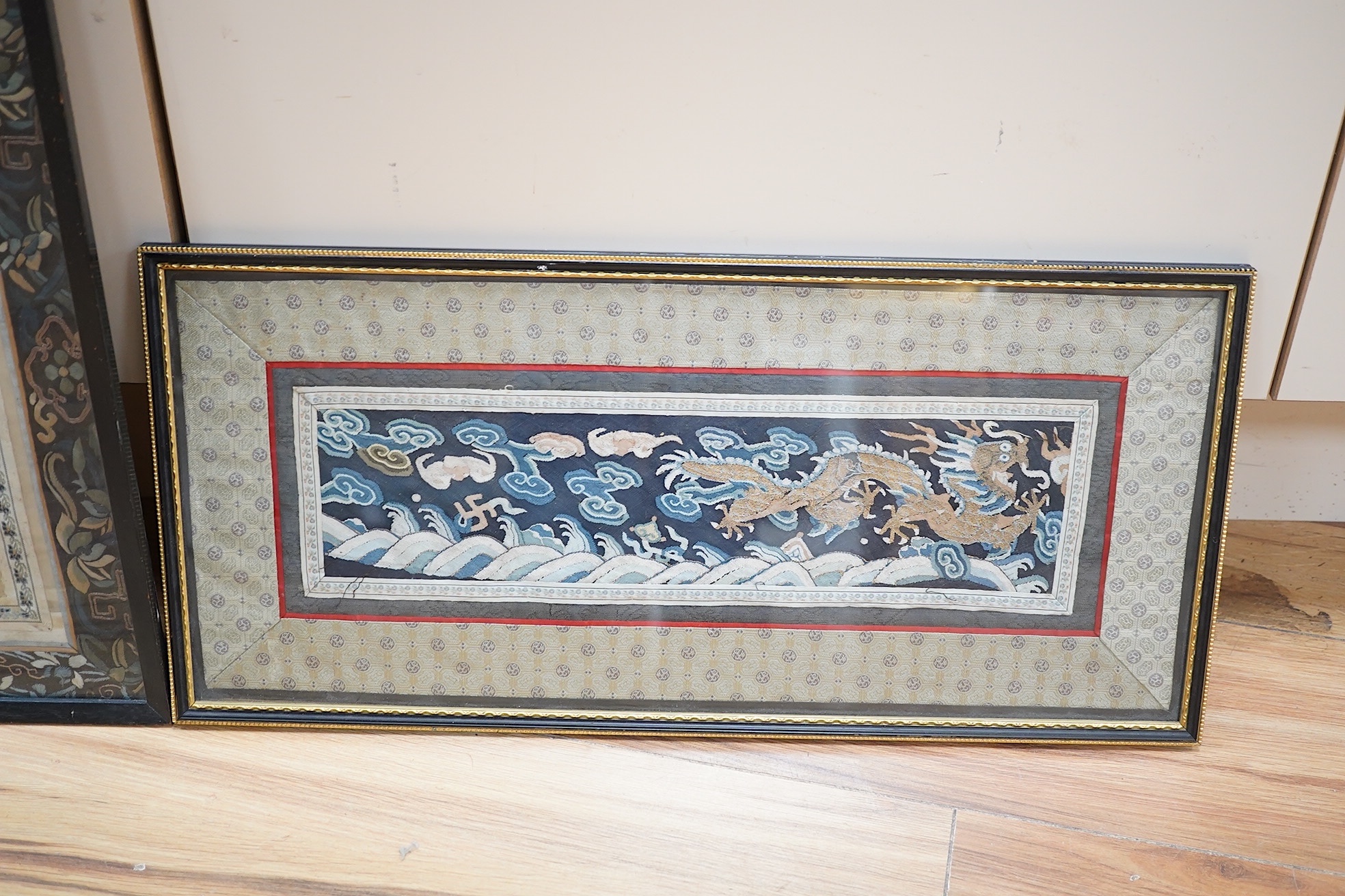 A Chinese framed Kesi gold dragon embroidery, probably originally part of a robe, together with a Chinese framed silk embroidered butterfly sleeve band, both items edged with narrow silk braiding and bordered with silk b